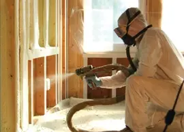 Technician applying spray foam insulation in a home.